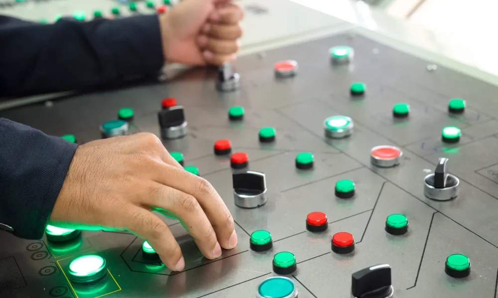 Closeup of lit lights and control dials on manufacturing machinery by controller