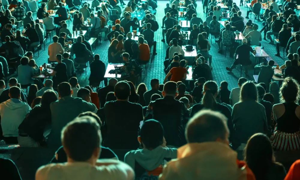 Sitting people watching football in a public place at night